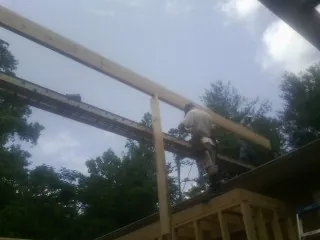 Carpenter setting a ridge beam over a new addition frame — Ice Dam Removal by Roofing Brothers in Folcroft