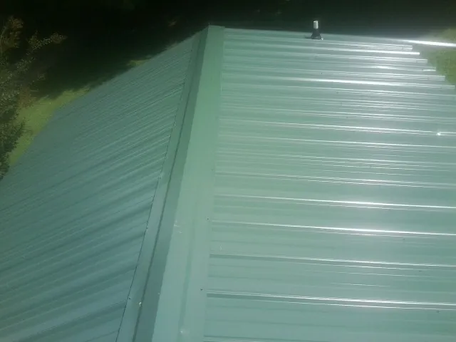 New green metal panels meeting at the ridge of a roof — Flat Roof Repair work by our crew in Folcroft