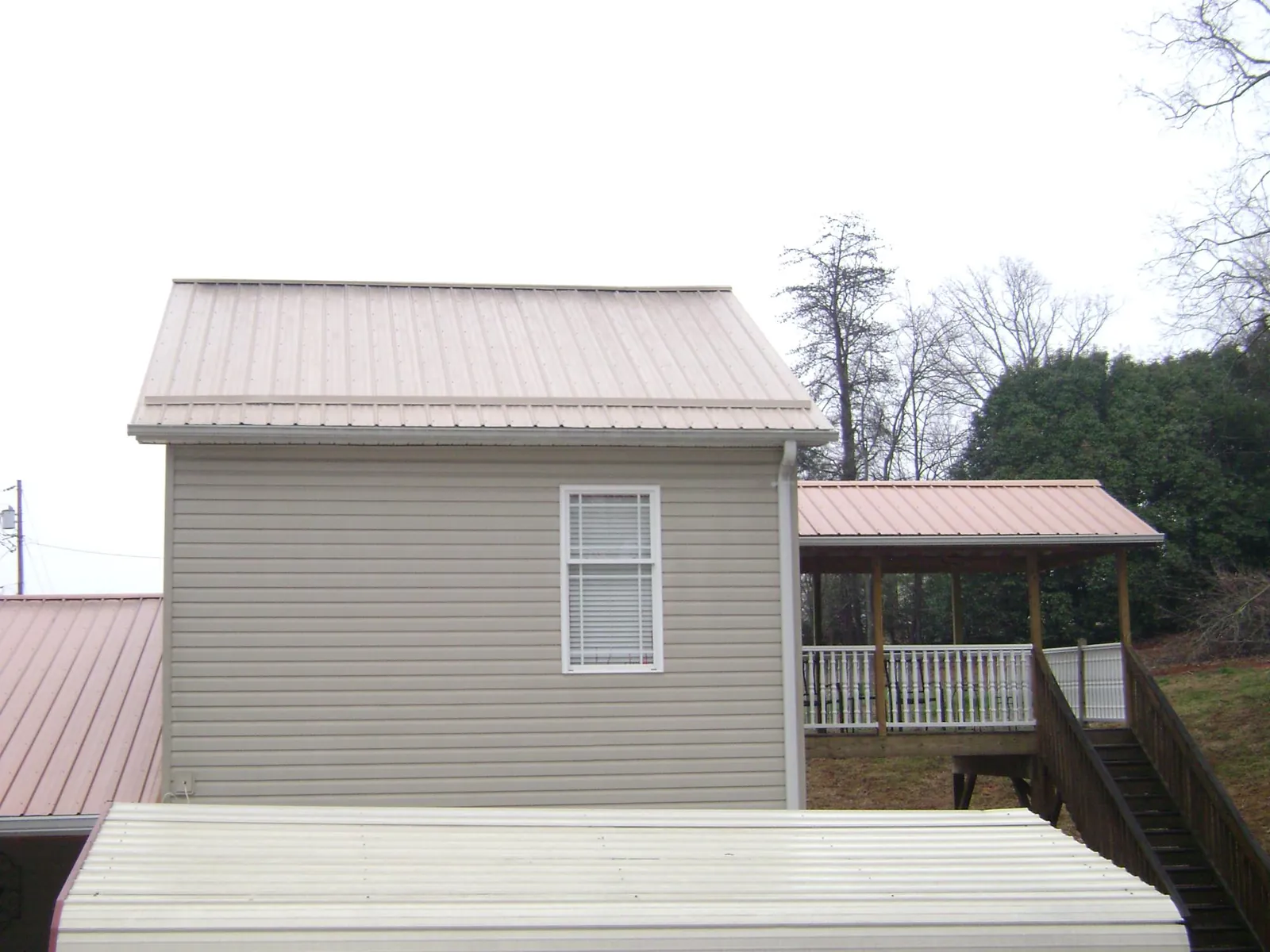 Tan metal roofs on a two story addition and attached porch, from a Roof Replacement job in Folcroft