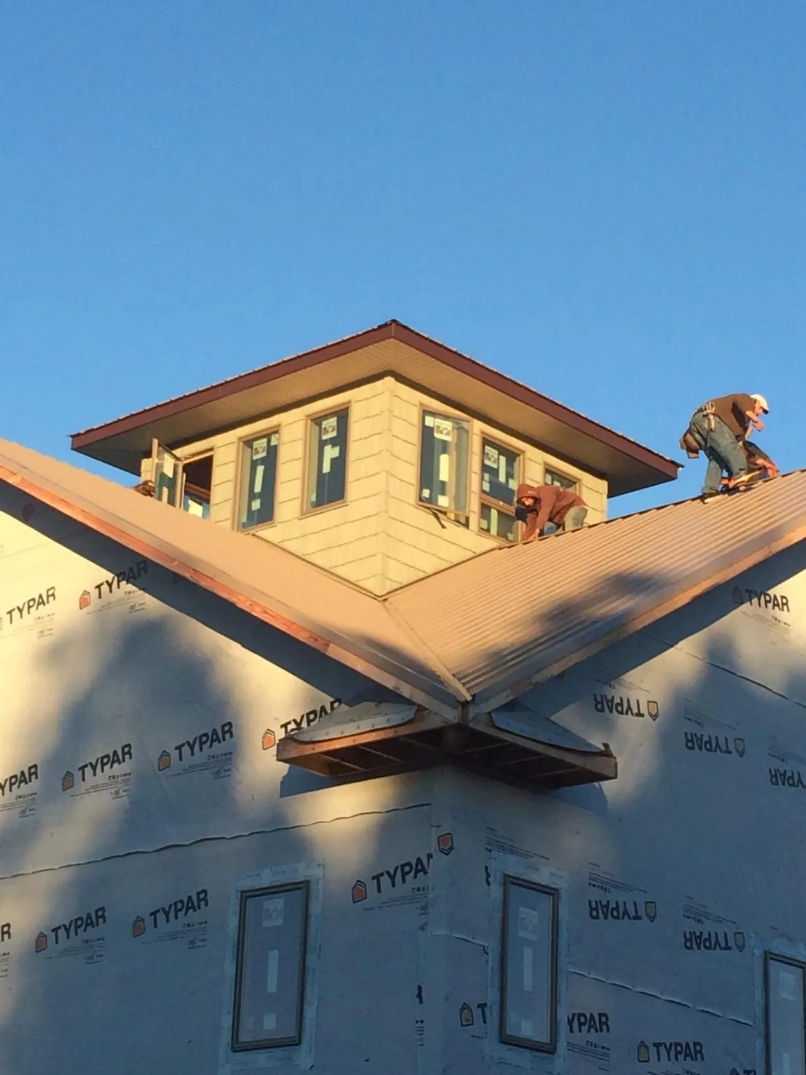 Roofers working around a rooftop cupola on a new metal roof at sunset — Roof Waterproofing in Folcroft by Roofing Brothers
